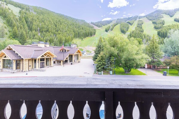 A lodge with a stone facade, large windows, and a mountain backdrop.