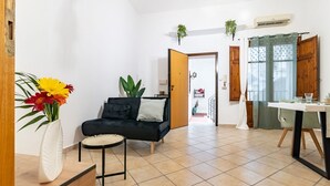 Un salon moderne avec un canapé noir, une petite table ronde et un vase de fleurs.