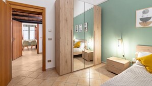 Une chambre à coucher avec un lit, une table de chevet, une commode et un grand miroir.