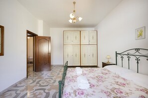 Une chambre à coucher comprenant un lit, une armoire, une table de chevet et un lustre.