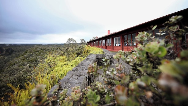 Un bâtiment rouge doté de grandes fenêtres donnant sur un paysage verdoyant et luxuriant.