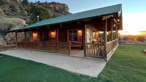 A wooden lodge with a porch, set against a mountainous backdrop. - The Peacemaker Cabin: Cozy cabin in enjoyable Apple Valley with AC (Apple Valley)