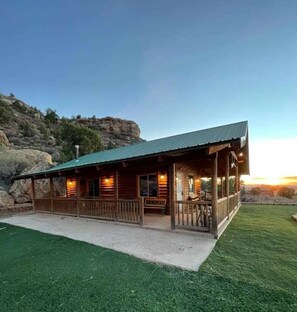 A wooden lodge with a porch, set against a mountainous backdrop. - The Peacemaker Cabin: Cozy cabin in enjoyable Apple Valley with AC (Apple Valley)