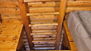 A wooden ladder leading to a lofted sleeping area in a log cabin. - The Peacemaker Cabin: Cozy cabin in enjoyable Apple Valley with AC (Apple Valley)