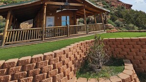 A rustic wooden cabin with a porch, surrounded by a brick wall and a small garden. - The Peacemaker Cabin: Cozy cabin in enjoyable Apple Valley with AC (Apple Valley)
