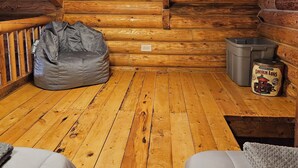 A cozy cabin with a wooden interior, a bean bag chair, a small table with a container, and a bed. - The Peacemaker Cabin: Cozy cabin in enjoyable Apple Valley with AC (Apple Valley)