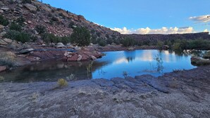 Un paisaje natural con un lago tranquilo, terreno rocoso y vegetación escasa.