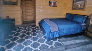 Un dormitorio de cabaña de madera con cama, alfombra y puerta.