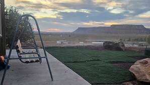 Un patio con un columpio, un sendero de hormigón y una zona de césped verde.