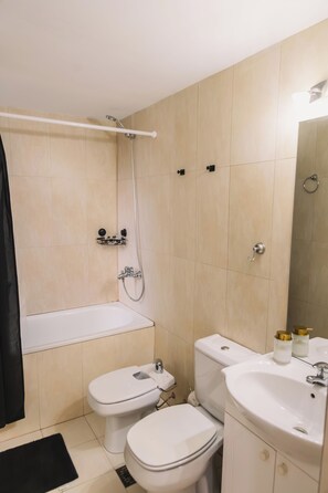 Bathroom features a bathtub, toilet, and sink with a mirror.