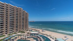 Un hôtel de grande hauteur doté de nombreux balcons donnant sur une plage et une piscine.
