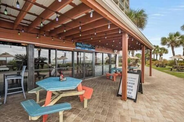 Une terrasse extérieure avec des tables et des chaises, un espace salon couvert et un panneau indiquant une salle privée.