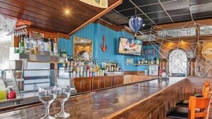 Un espace bar doté d’un comptoir en bois, de tabourets de bar et d’une variété de bouteilles et de verres.