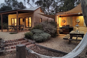 A rustic cabin with a covered patio, a barbecue area, and a hammock. - Muckleford Forest Cottage - Quiet bush stay with dam, pizza oven & wood fire (Muckleford)