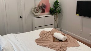A bedroom with a bed, a ceiling fan, a TV mounted on the wall, a door, a plant, and a painting. - Chic 1-bedroom 1-bath house with AC and WiFi in the heart of Atlanta (Atlanta)