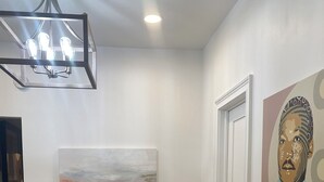 A dining area with a round wooden table, white chairs, pink bowls, and a modern chandelier. - Chic 1-bedroom 1-bath house with AC and WiFi in the heart of Atlanta (Atlanta)