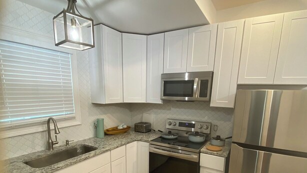 A modern kitchen with white cabinets, stainless steel appliances, a microwave, stove, and refrigerator. - Chic 1-bedroom 1-bath house with AC and WiFi in the heart of Atlanta (Atlanta)