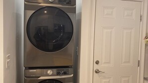 A laundry room with two stacked Samsung washing machines and a white door. - Chic 1-bedroom 1-bath house with AC and WiFi in the heart of Atlanta (Atlanta)