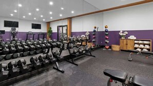 Ein Fitnessraum mit Gewichthebern, einem Spiegel und einem Fernseher an der Wand.