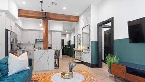 A modern living room with a sofa, a coffee table, and a TV. - LUXE Suite 2BR 2BA Steps from Superdome Hotel (New Orleans)