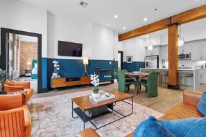A modern living room with a sofa, coffee table, and a dining area with chairs.