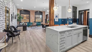 A modern kitchen with a marble island, a dining area with a brick wall, and a seating area with a patterned wall.