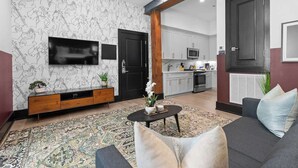 Un soggiorno con divano, tavolino, televisore e tappeto decorato.
