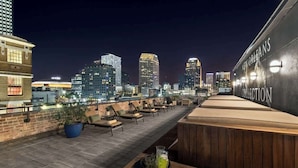 A rooftop terrace with a city skyline view, lounge chairs, and a bar area.