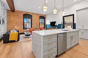 A modern kitchen with a marble countertop, stainless steel appliances, and a large island with drawers.