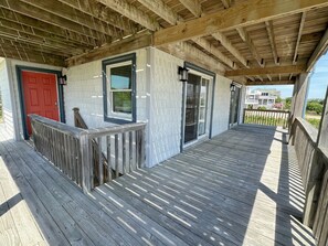A wooden deck with a red door and windows, leading to a covered porch area. - Second Wind: Oceanside with Views, Close to Beach and Lighthouse! (Corolla)