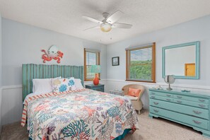 A bedroom with a bed, a dresser, a chair, a ceiling fan, and a window with blinds.