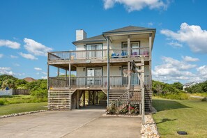 A two-story building with a balcony, a basketball hoop, and a covered walkway. - Second Wind: Oceanside with Views, Close to Beach and Lighthouse! (Corolla)