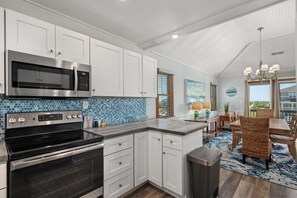 A modern kitchen with white cabinets, stainless steel appliances, and a blue-tiled backsplash. - Second Wind: Oceanside with Views, Close to Beach and Lighthouse! (Corolla)