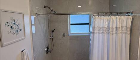 Un baño moderno con ducha de vidrio, inodoro y una ventana pequeña.