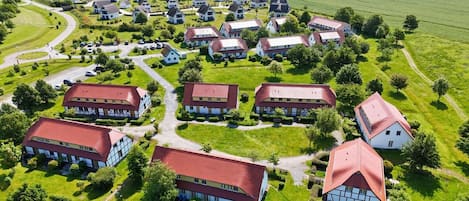 An aerial view of a residential area with multiple houses, each featuring a red roof and a mix of white and dark-colored walls.