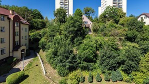 Un quartier résidentiel comprenant deux immeubles à logements de grande hauteur, entouré d’une végétation luxuriante et bordé d’un sentier bien entretenu.