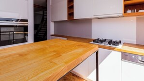 Une cuisine moderne avec des meubles blancs, un plan de travail en bois, un four encastré et un lave-vaisselle Bosch.