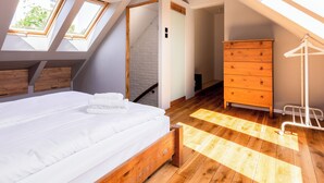 Une chambre à coucher avec un lit en bois, une commode et une lucarne.