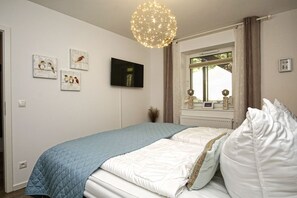 Une chambre à coucher avec un lit, une télévision et des œuvres d’art accrochées au mur.