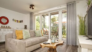 A living room with a sofa, a coffee table, and a view of the outdoors.