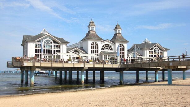 A pier with a white building featuring large windows and a central tower.