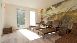 A sunlit room with wicker furniture, large windows, and a beach mural.