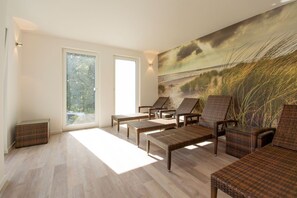 Habitación luminosa con muebles de mimbre, ventanas amplias y un mural con motivos playeros.