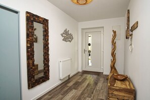 A hallway with a wooden-framed mirror, a radiator, and a wooden sculpture.