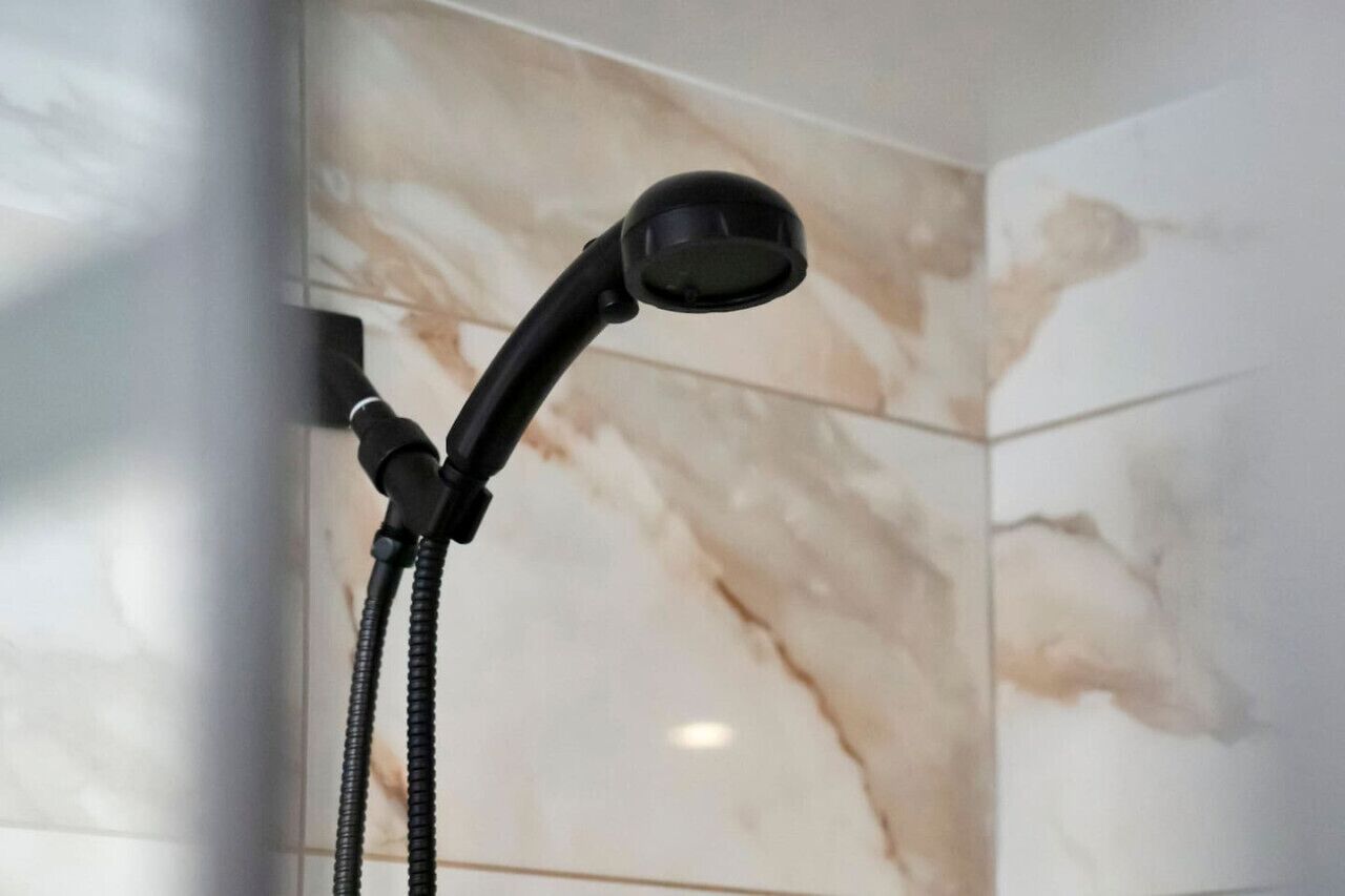 Ein Duschkopf mit flexiblem Schlauch in einem Badezimmer mit Marmorwänden.
