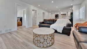 Ein geräumiges Wohnzimmer mit einer Ledersofa, einem runden Couchtisch und einer Küche im Hintergrund.