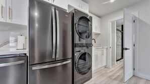 Una cocina moderna con electrodomésticos de acero inoxidable, armarios blancos y suelo de madera.