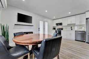 Una cocina moderna con armarios blancos, un refrigerador de acero inoxidable y un microondas.