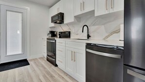 Una cocina moderna con armarios blancos, electrodomésticos de acero inoxidable y un salpicadero de mármol.