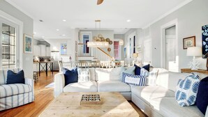 Un salon spacieux avec un grand canapé, une table basse et un coin repas à l’arrière-plan.